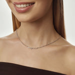 Silver name necklace worn by a model on a neutral background