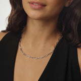 Silver paperclip chain necklace worn by a person against a neutral background