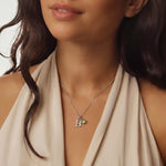 Close-up of a woman wearing a silver necklace with a 'B' pendant and birthstone.