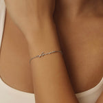 Silver bracelet on a person's wrist with a neutral background