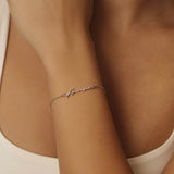 Silver bracelet on a person's wrist with a neutral background