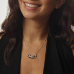 Woman wearing a silver bubble necklace with 'EMILY' pendant against a neutral background