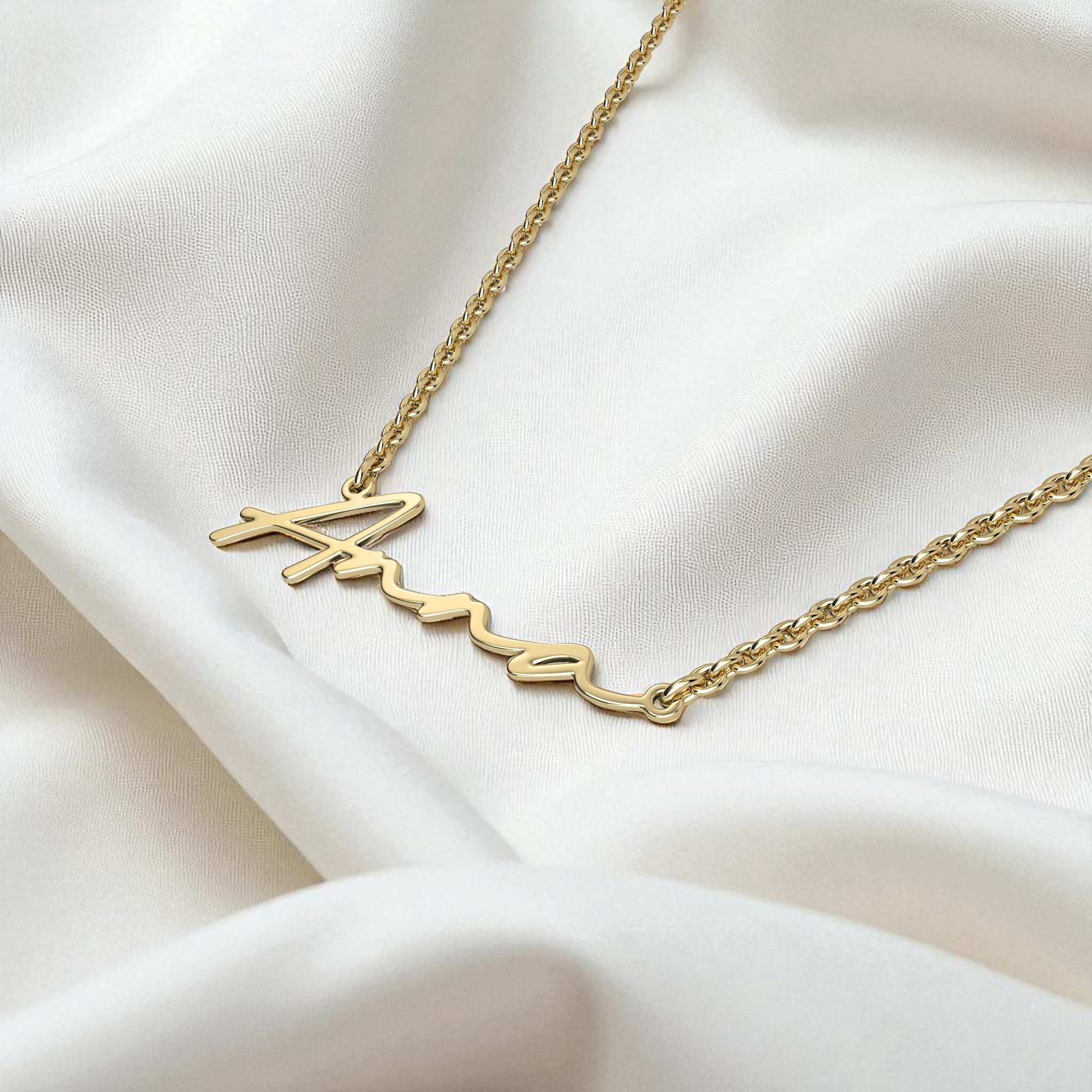 Gold necklace with 'Anna' pendant on a white fabric background