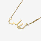 Gold necklace with Arabic script on a white background