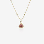 Gold necklace with a red birthstone pendant on a white background