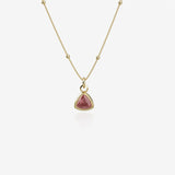 Gold necklace with a red birthstone pendant on a white background
