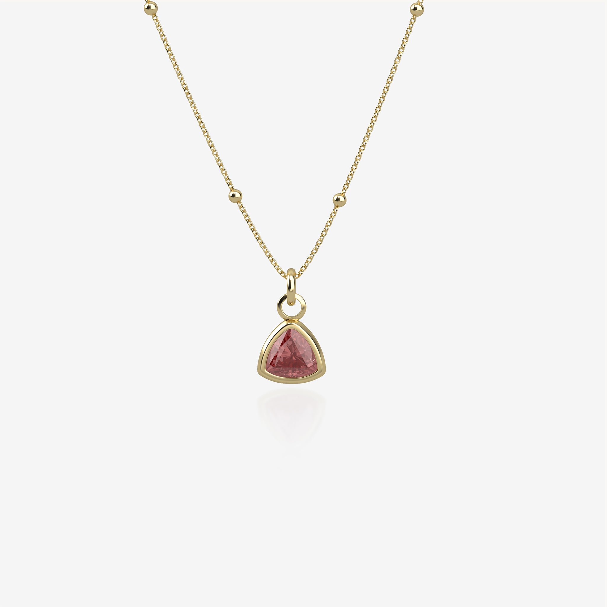 Gold necklace with a red birthstone pendant on a white background