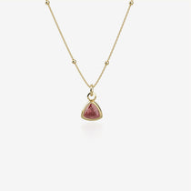 Gold necklace with a red birthstone pendant on a white background