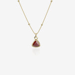 Gold necklace with a red birthstone pendant on a white background