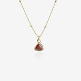 Gold necklace with a red birthstone pendant on a white background