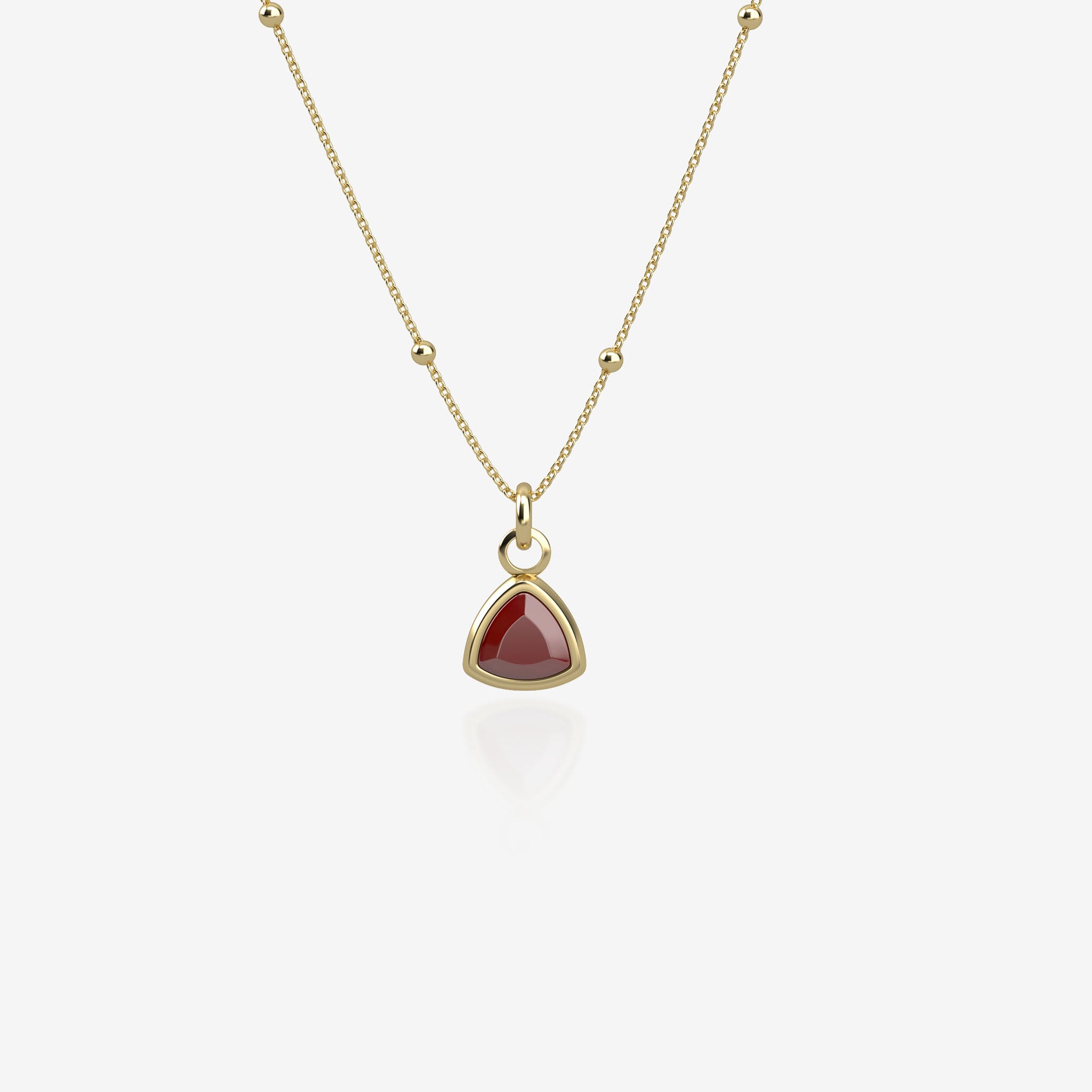 Gold necklace with a red birthstone pendant on a white background