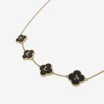 Gold necklace with black clover-shaped pendants with initials on a white background