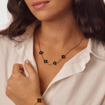 Necklace with black clover pendants worn by a person in a white shirt.