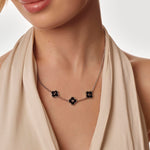 Necklace with black flower clover worn by a model against a neutral background