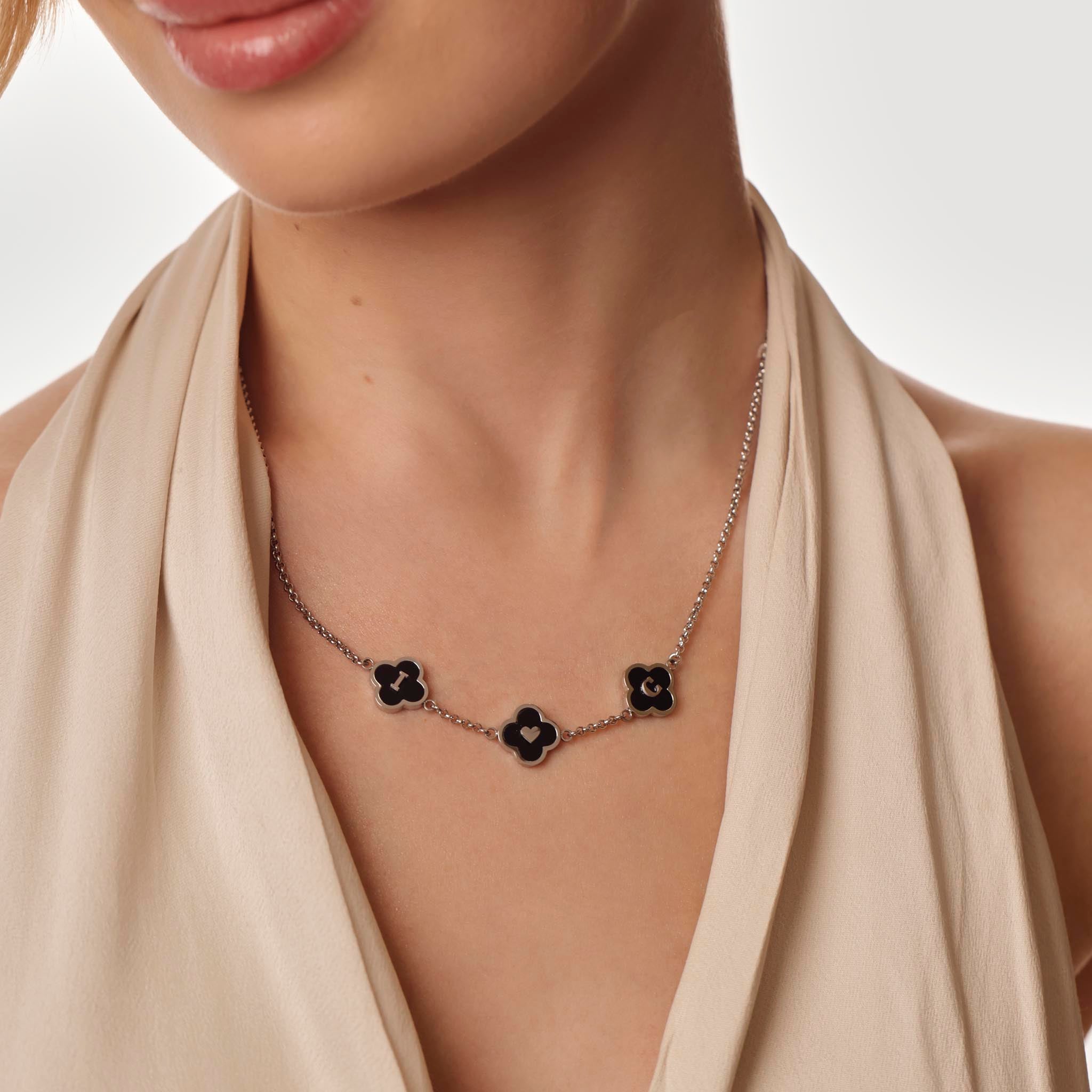 Necklace with black flower clover worn by a model against a neutral background