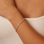 Delicate classic tennis bracelet on a wrist with a neutral background