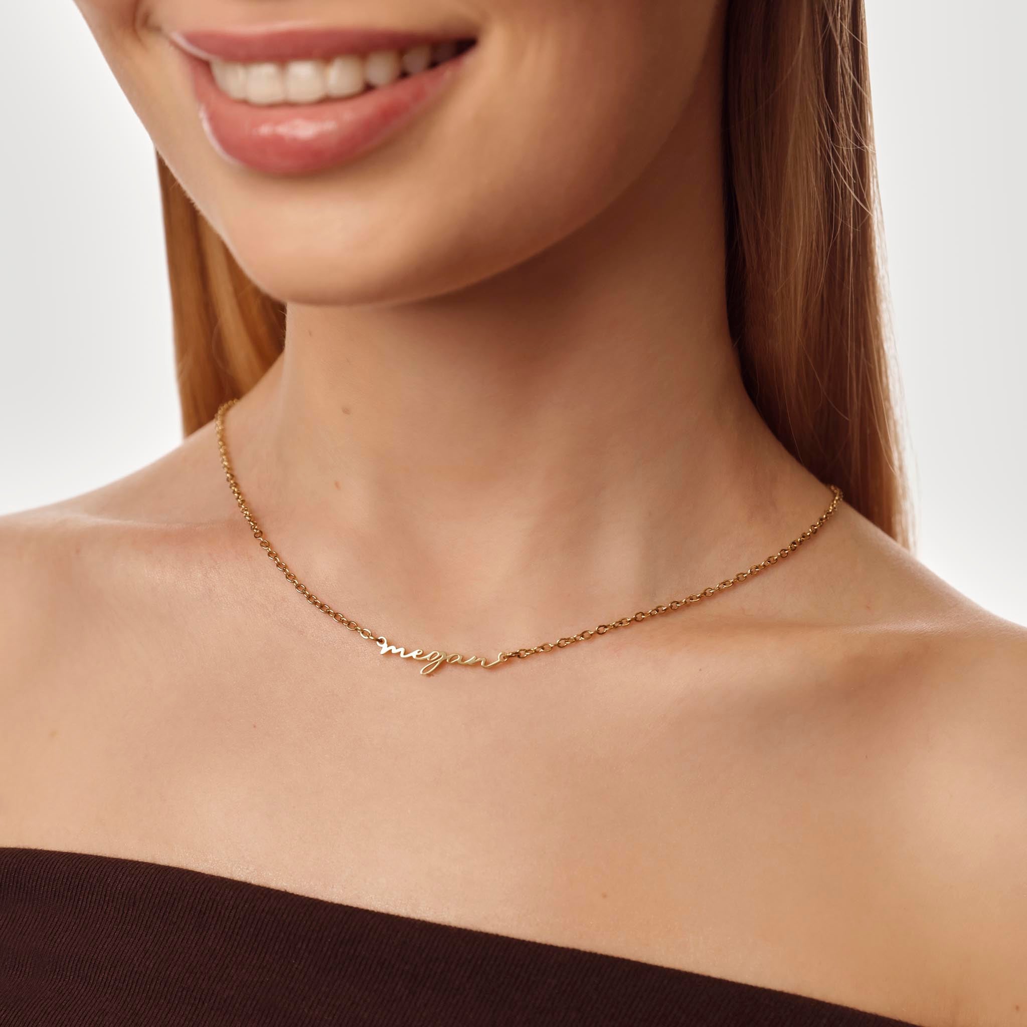 Gold name necklace worn by a model on a neutral background