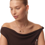 Woman wearing a gold necklace with two pendants on a white background