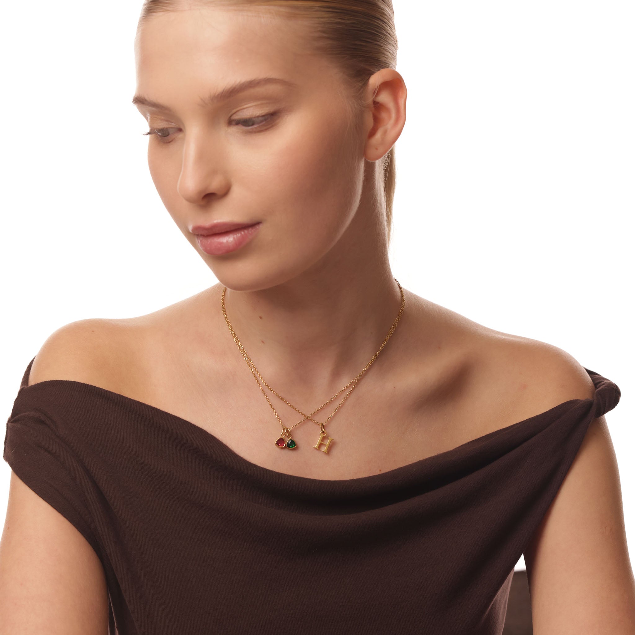 Woman wearing a gold necklace with two pendants on a white background