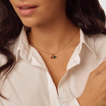 Close-up of a person wearing a delicate necklace with small birthstone pendants against a neutral background