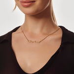 Gold necklace with 'Charlotte' engraving on a person wearing a black top against a neutral background
