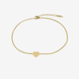 Gold bracelet with a heart-shaped tag with engraving on a white background