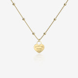 Gold necklace with a heart-shaped pendant with engraving on a white background