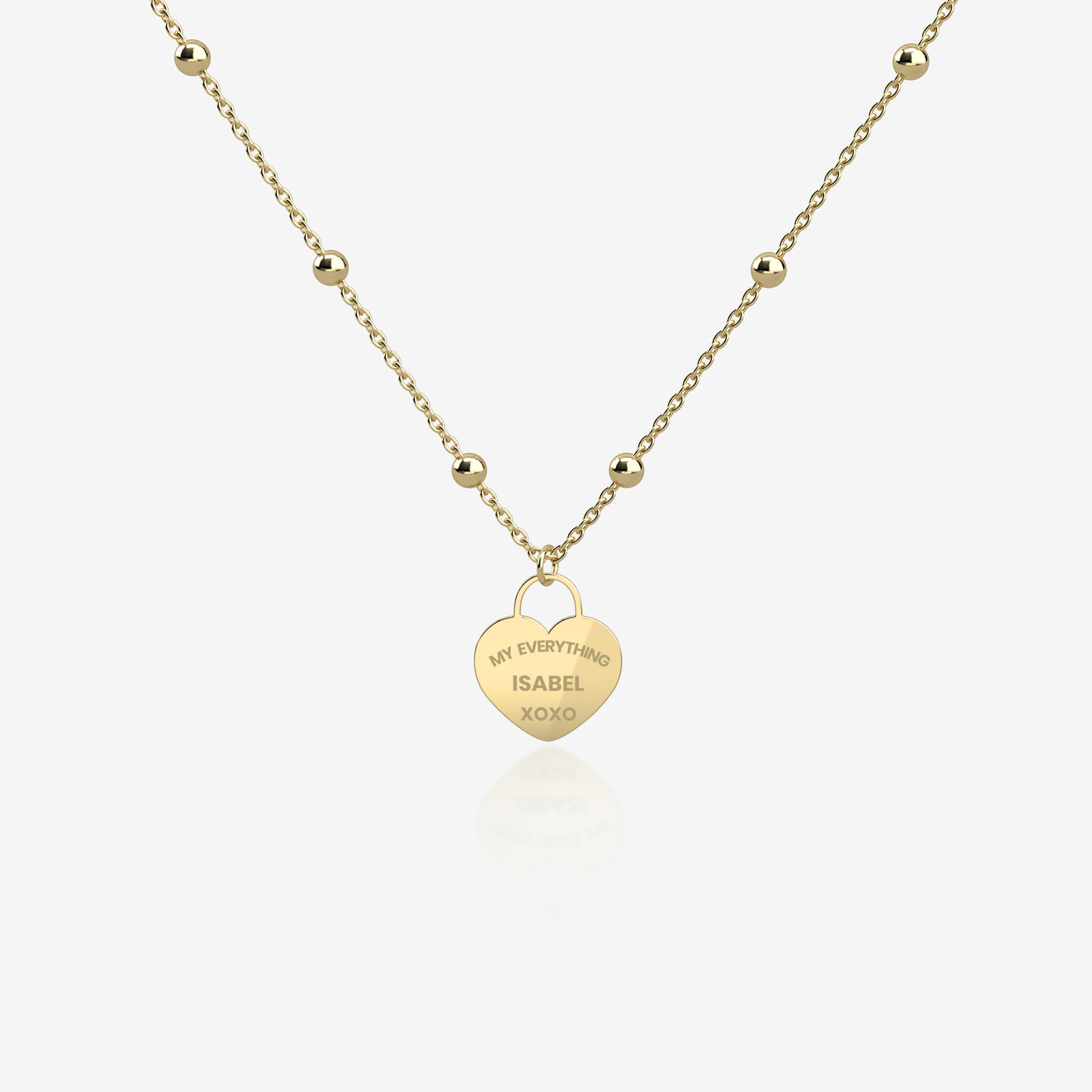 Gold necklace with a heart-shaped pendant with engraving on a white background