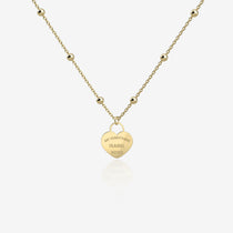 Gold necklace with a heart-shaped pendant with engraving on a white background
