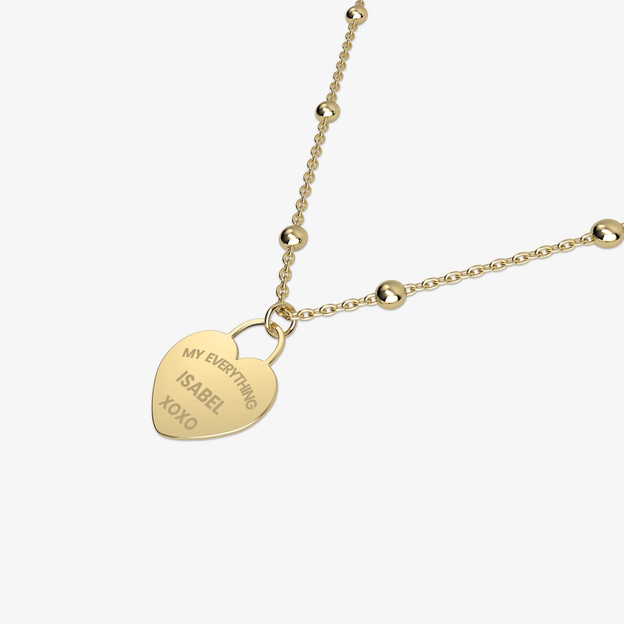 Gold necklace with a heart-shaped pendant with engraving on a white background