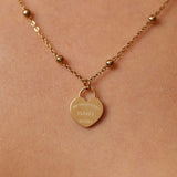 Gold necklace with a heart-shaped pendant on a beige background