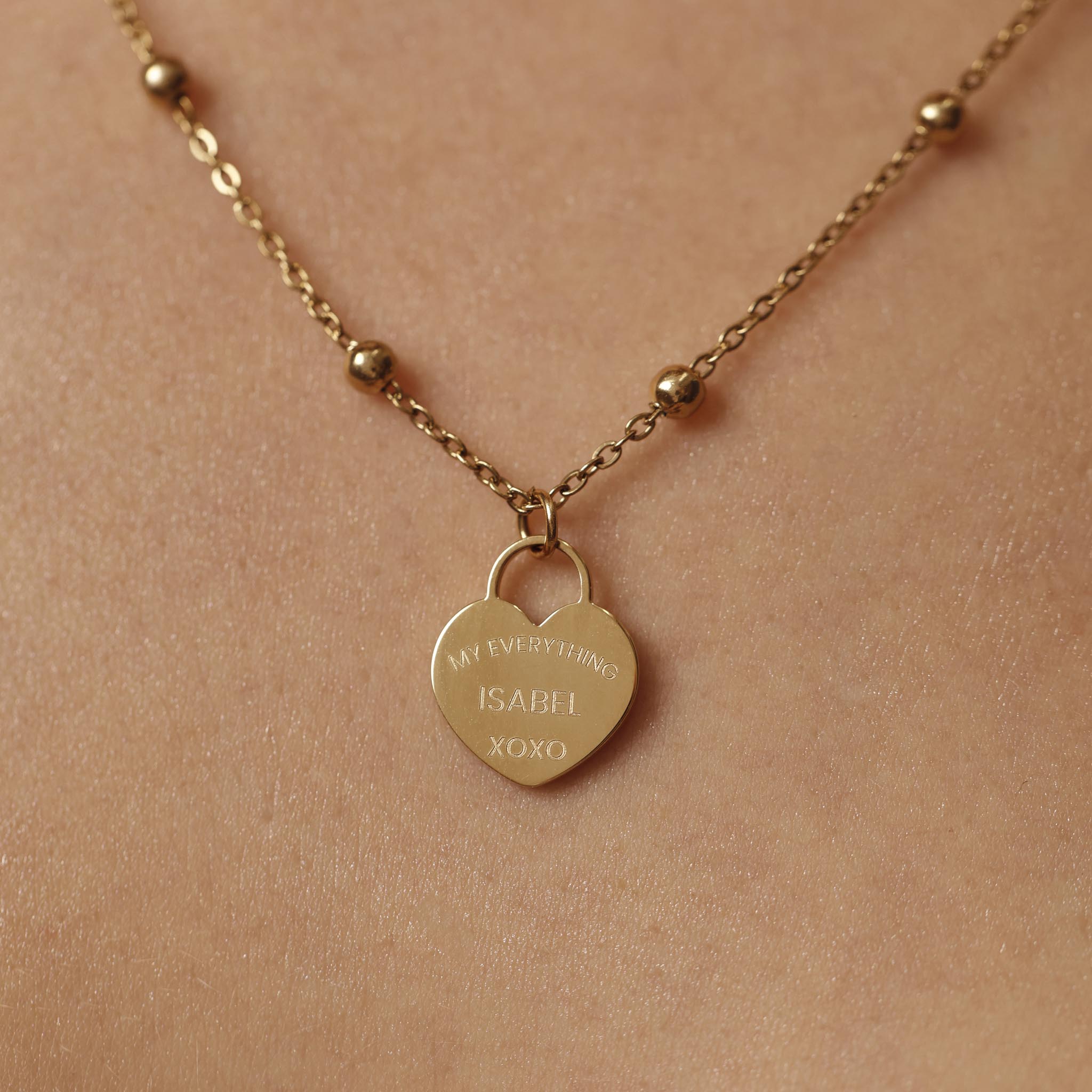 Gold necklace with a heart-shaped pendant on a beige background