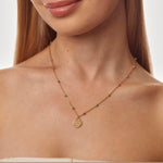 Gold necklace with a heart-shaped pendant on a model against a neutral background