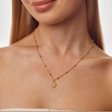 Gold necklace with a heart-shaped pendant on a model against a neutral background