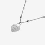 Silver necklace with a heart-shaped pendant with engraving on a white background