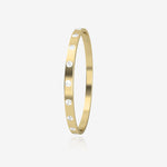 Gold bangle with embedded diamonds on a light beige background