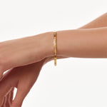 Gold eternity bangle on a person's wrist against a white background