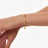 Gold eternity bangle on a person's wrist against a white background