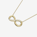 Gold infinity necklace with diamonds on a white background