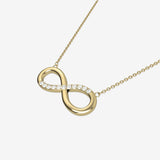 Gold infinity necklace with diamonds on a white background