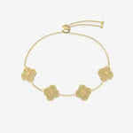 Gold bracelet with clover-shaped charms displaying initials on a white background