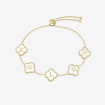 Gold bracelet with clover-shaped charms displays initials on a white background