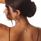 Woman wearing a gold necklace with a 'K' pendant on a white background
