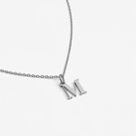 Silver necklace with a 'M' pendant on a light gray background