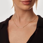 Gold necklace with 'Mama' engraving on a person wearing a black top.
