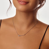 Close-up of a woman wearing a delicate necklace with a Mama design.