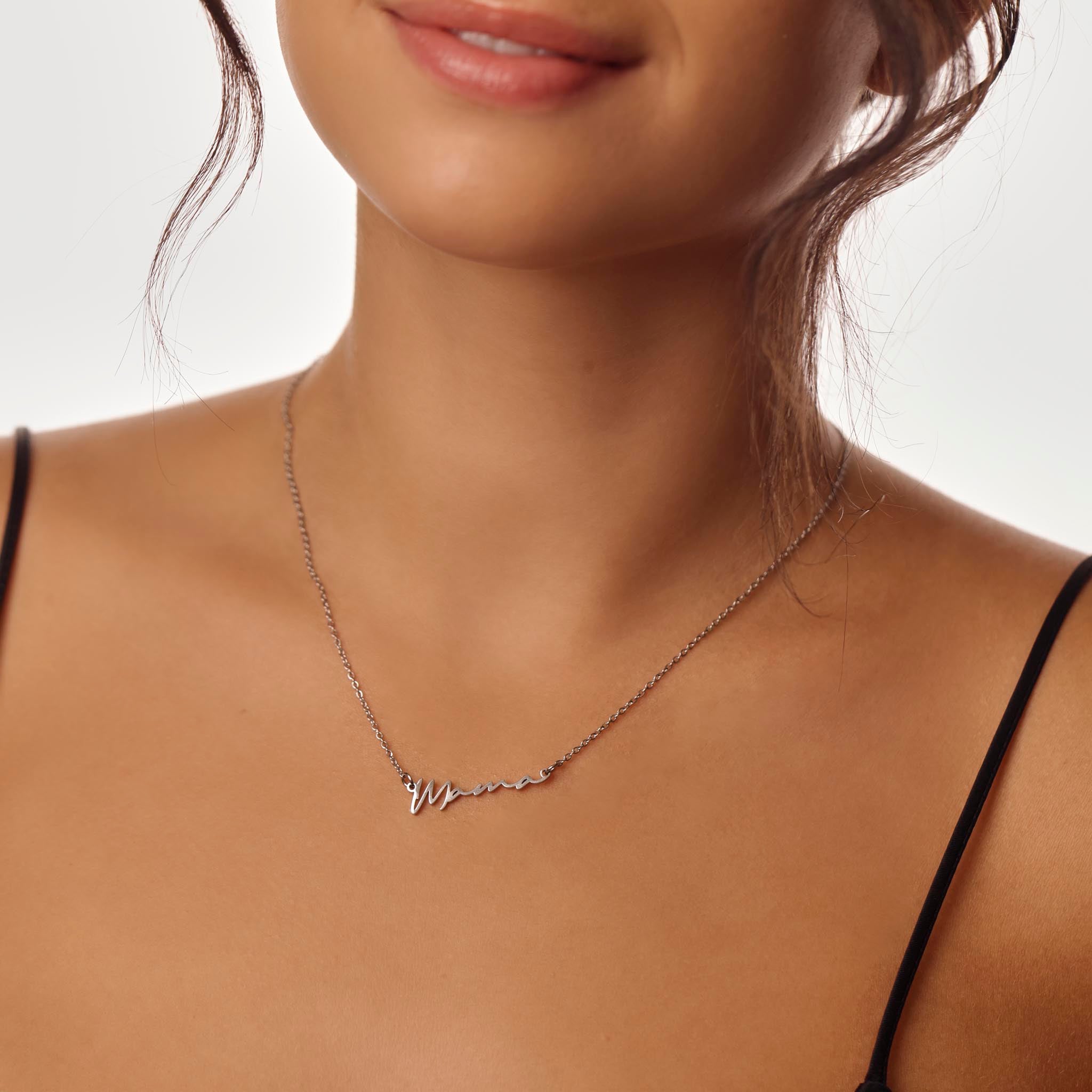 Close-up of a woman wearing a delicate necklace with a Mama design.