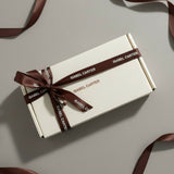 White gift box with brown ribbon and 'Isabel Carter' branding on a light gray background