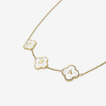 Gold necklace with clover-shaped pendants featuring initials on a white background