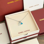Necklace with a 'B' charm and march aquamarine birthstone pendant in an Isabel Carter box